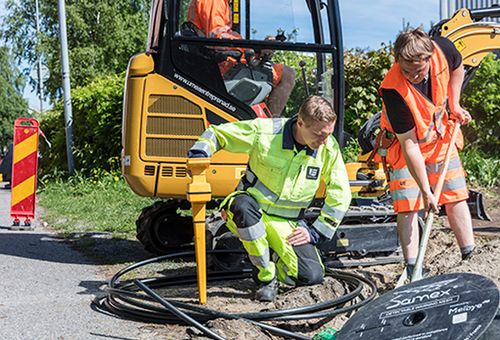 Bild på två personer som lägger ner kabel