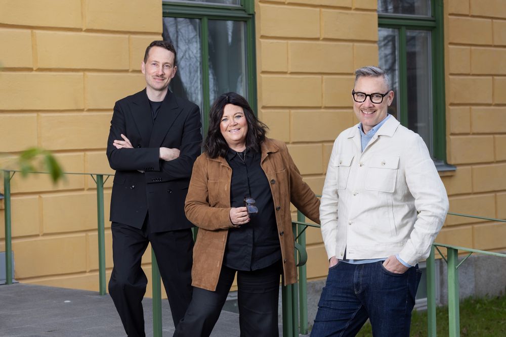 Tre personer ler och tittar in mot kameran.