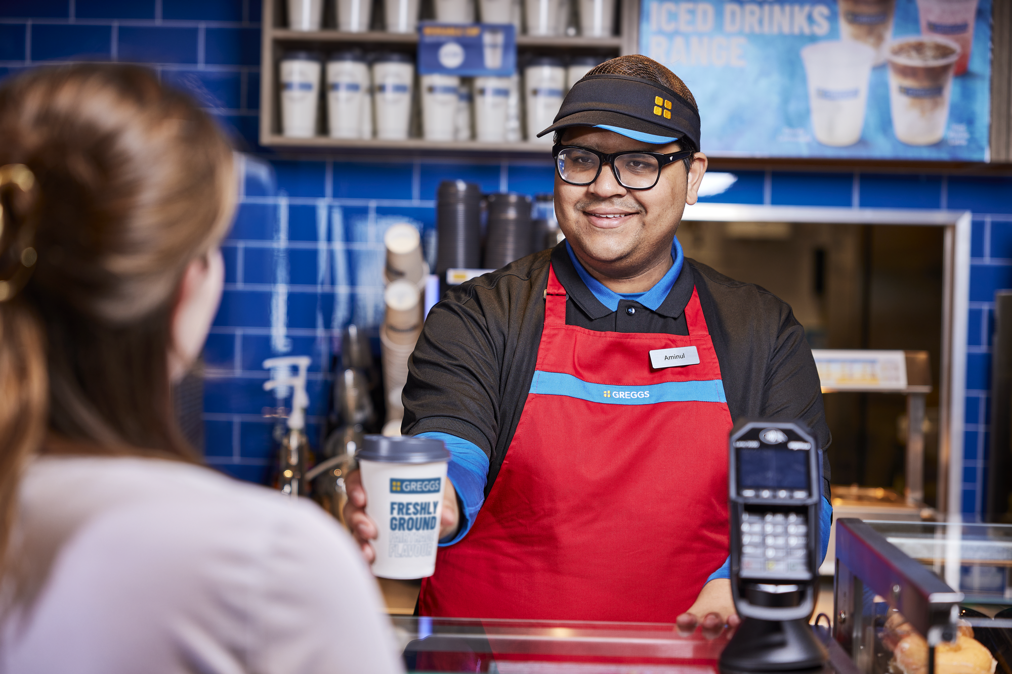 Colleague handing customer hot drink