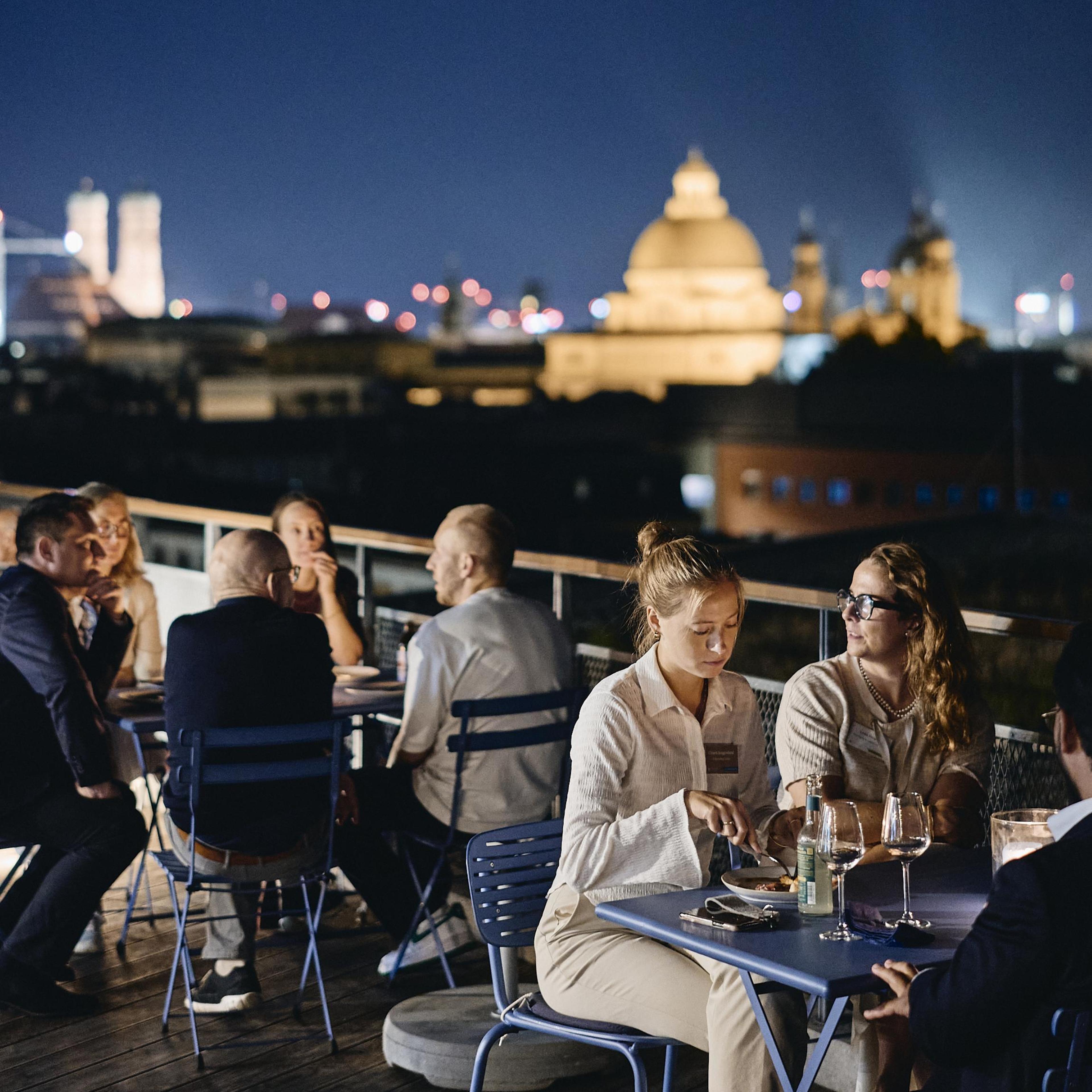 Gäste am Tisch auf der Dachterrasse beim Abendessen