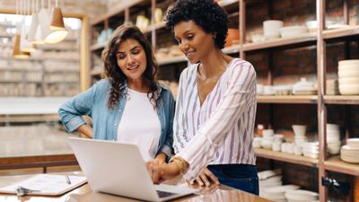 Two woman in pottery store working on computer together