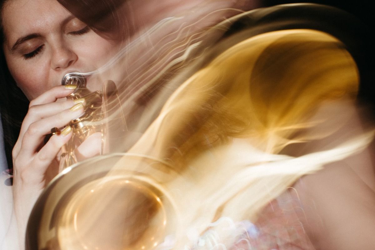 Woman playing a trumpet with eyes closed, blurred motion effect capturing the instrument's golden shine and movement.