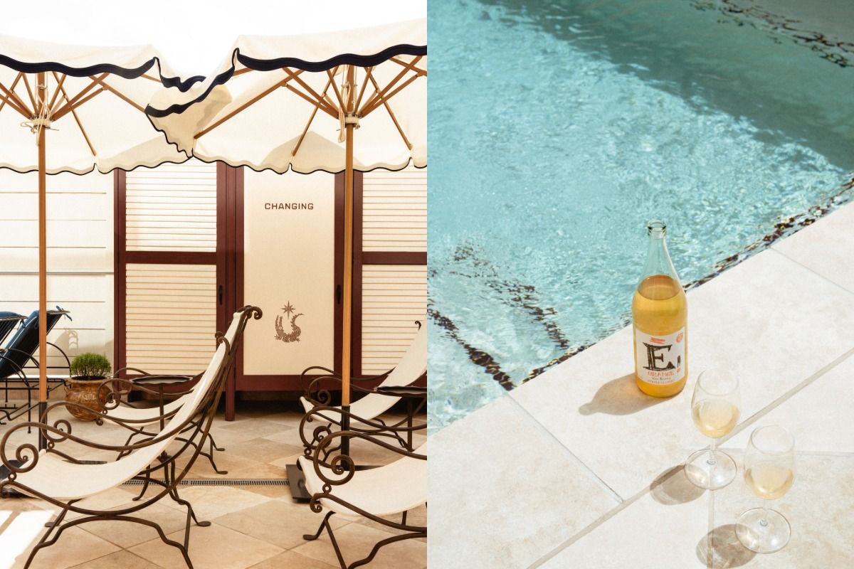 Poolside scene with lounge chairs, umbrellas, and a changing room; a bottle of beverage and filled glasses sit by the pool.