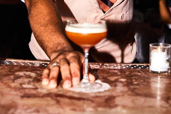 A photo of a bartender serving a pink cocktail at Candy Bar