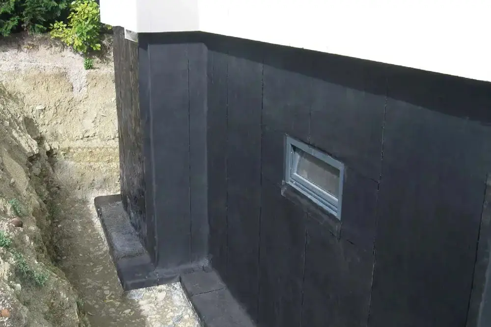 Außenwand eines Kellers mit Abdichtungsbahnen, die das Eindringen von Feuchtigkeit und Radon verhindern.