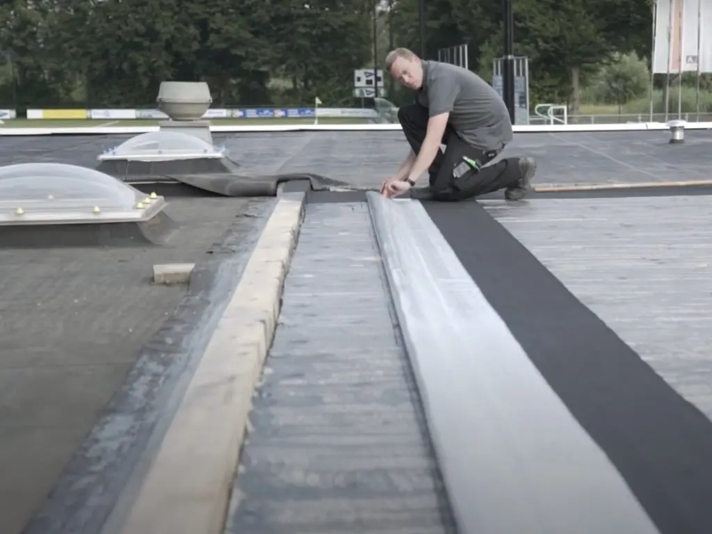 Verarbeiter verlegt RESITRIX EPDM-Bahn auf einem Bitumendach