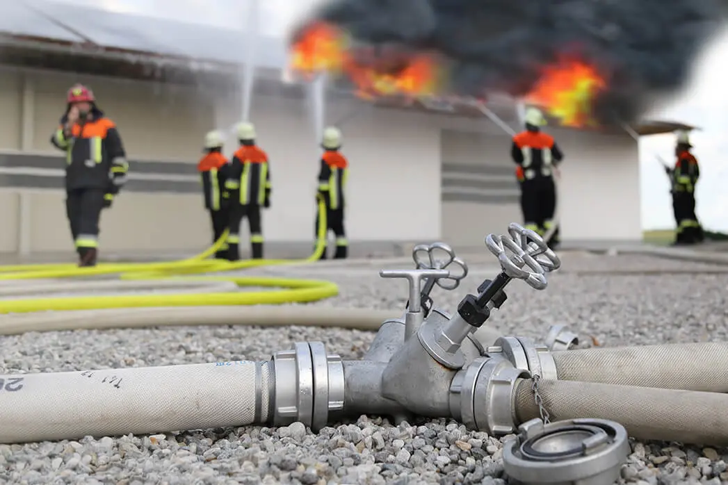 Feuerwehrleute löschen ein brennendes Dach einer Lagerhalle