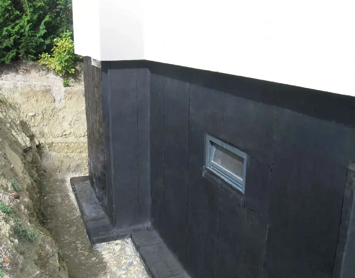 Kellerabdichtung von außen mit EPDM-Abdichtungsbahn an einer freigelegten Kellerwand mit Fenster und Sockelbereich