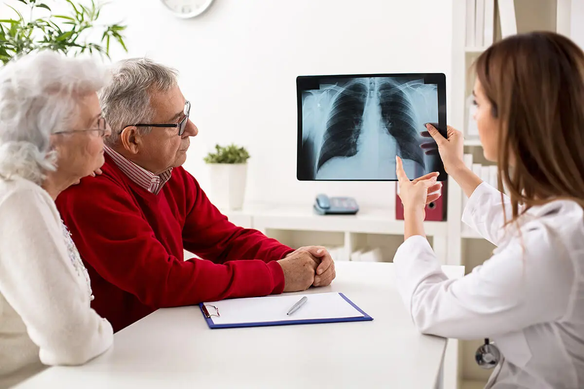 Ärztin zeigt einem älteren Paar ein Röntgenbild der Lunge, um mögliche gesundheitliche Auswirkungen von Radon wie Lungenkrebs zu besprechen