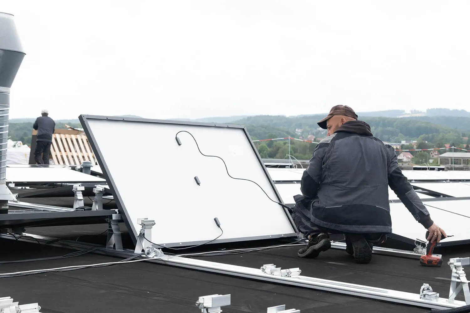 Handwerker befestigt eine Solaranlage auf dem Flachdach