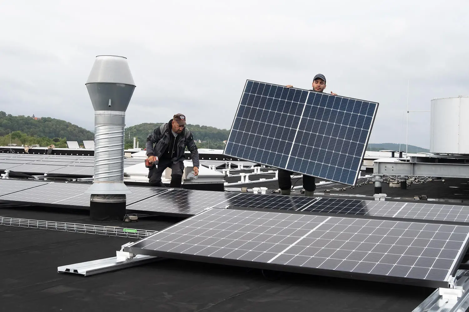Handwerker befestigen Solarmodule auf einem Flachdach