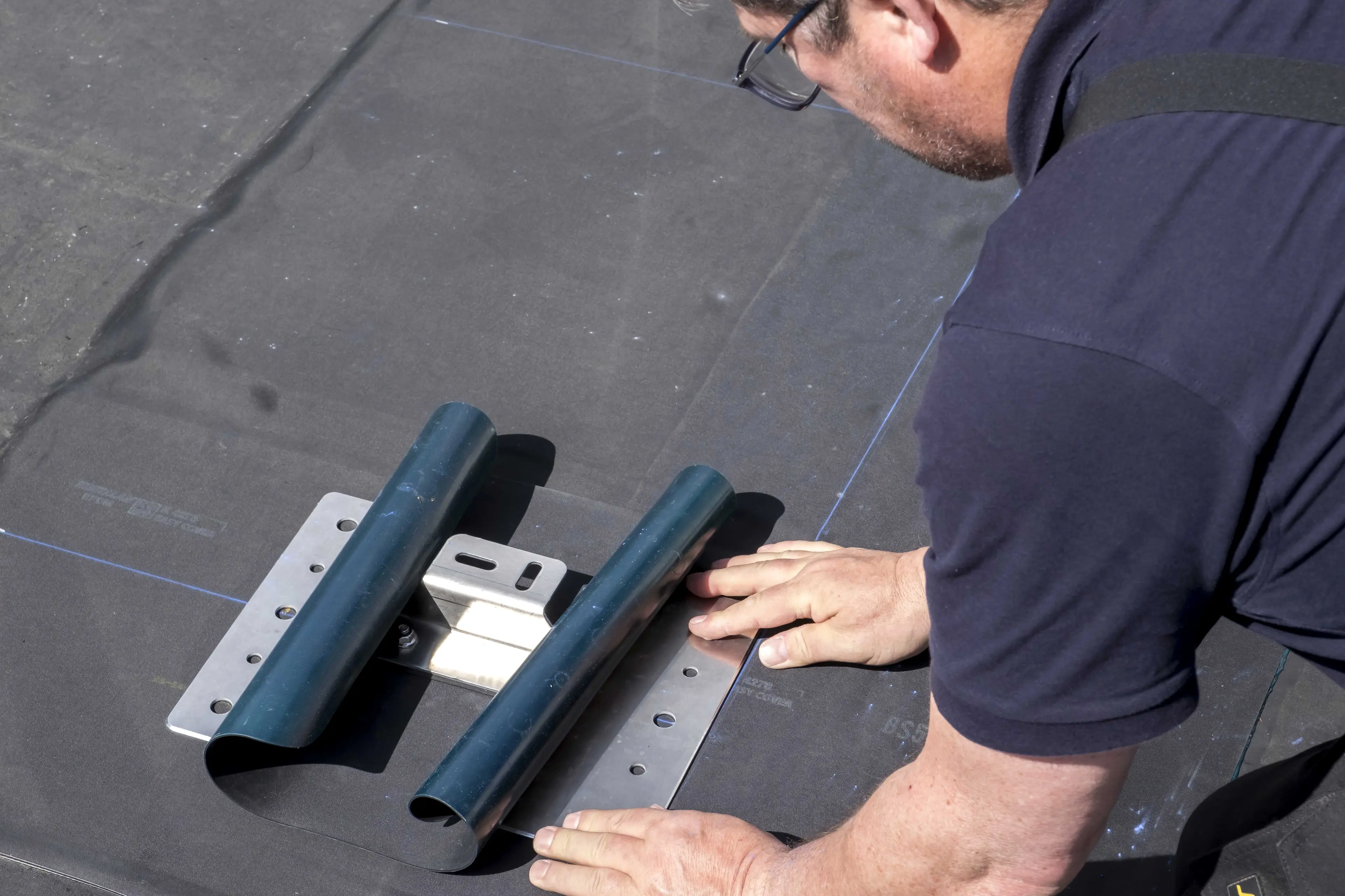 Ein Dachhandwerker dichtet eine Solarhalterung mit einer EPDM-Manschette ab