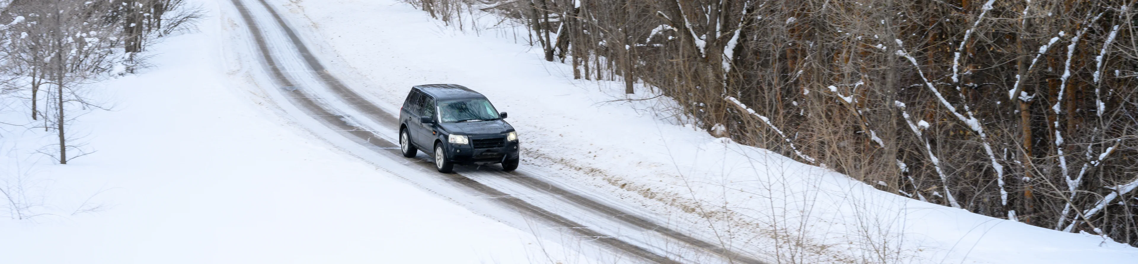 Car driving along a snow-covered road in winter conditions