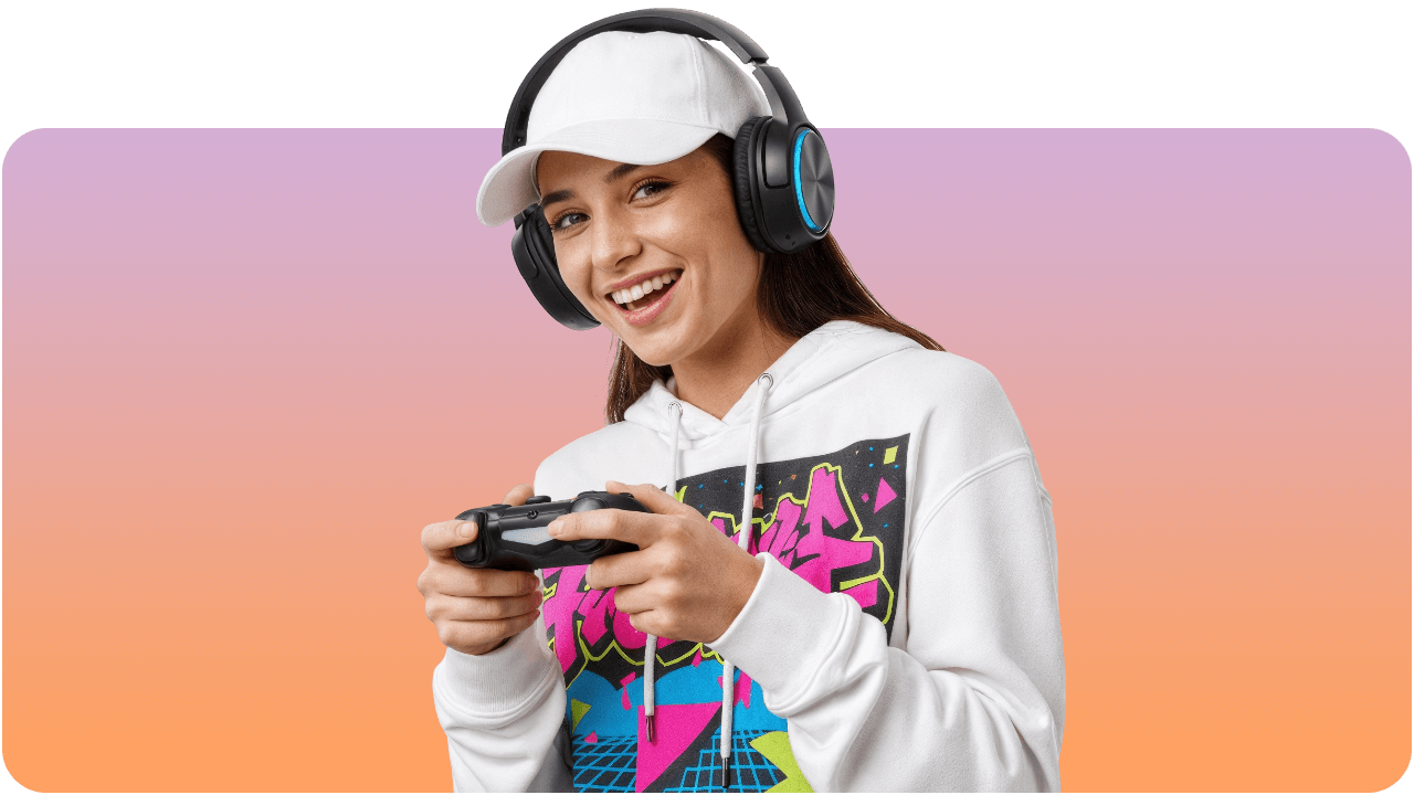 A smiling person wearing a white cap and hoodie plays a video game with headphones on against a pink and orange gradient background.