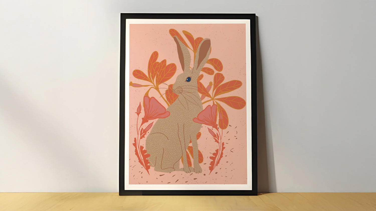 Framed artwork of a rabbit with large ears, surrounded by orange and pink leaves, set against a soft pink background.