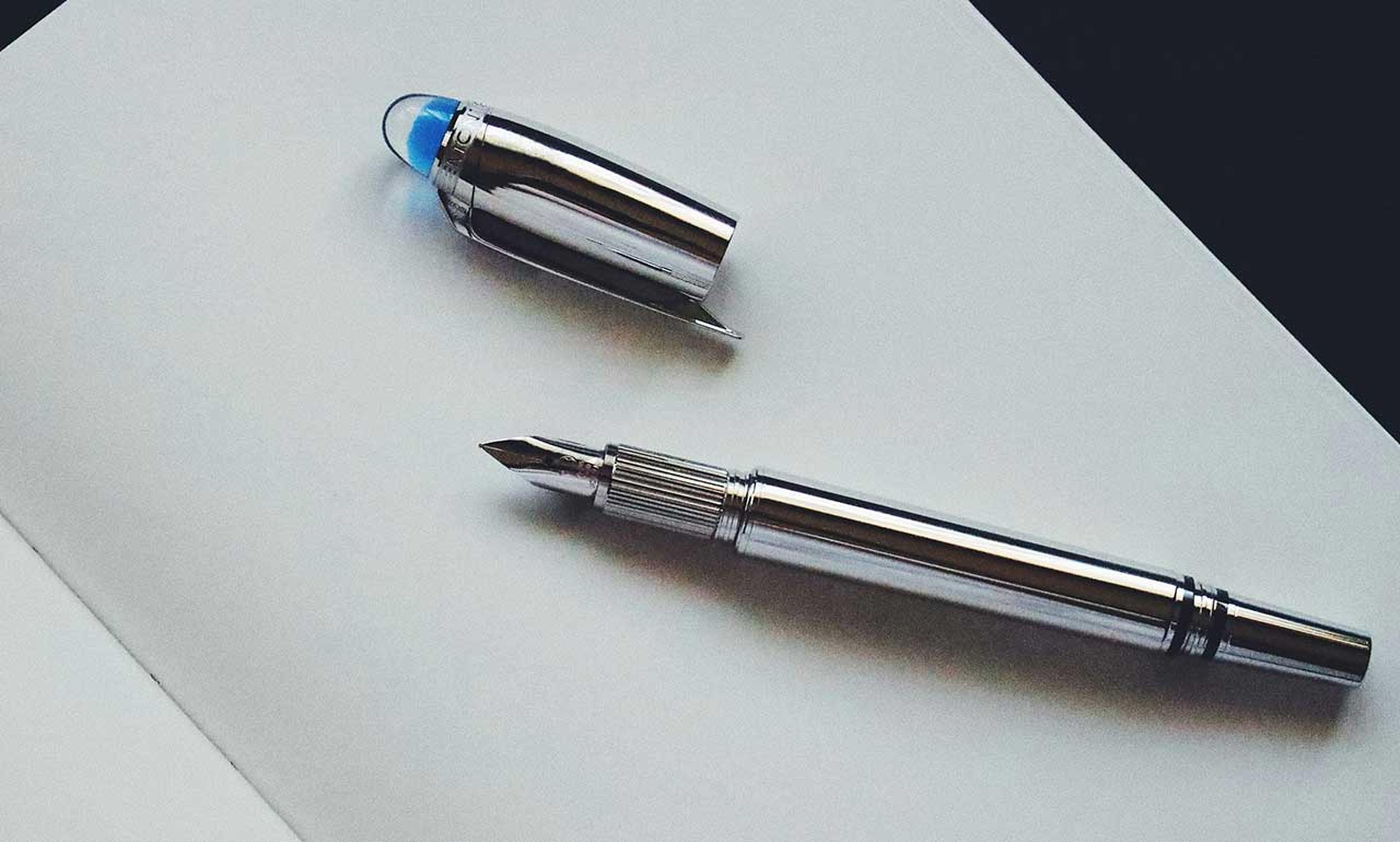 Silberner Füllfederhalter ohne Kappe, auf einer leeren Seite eines Notizbuchs liegend.