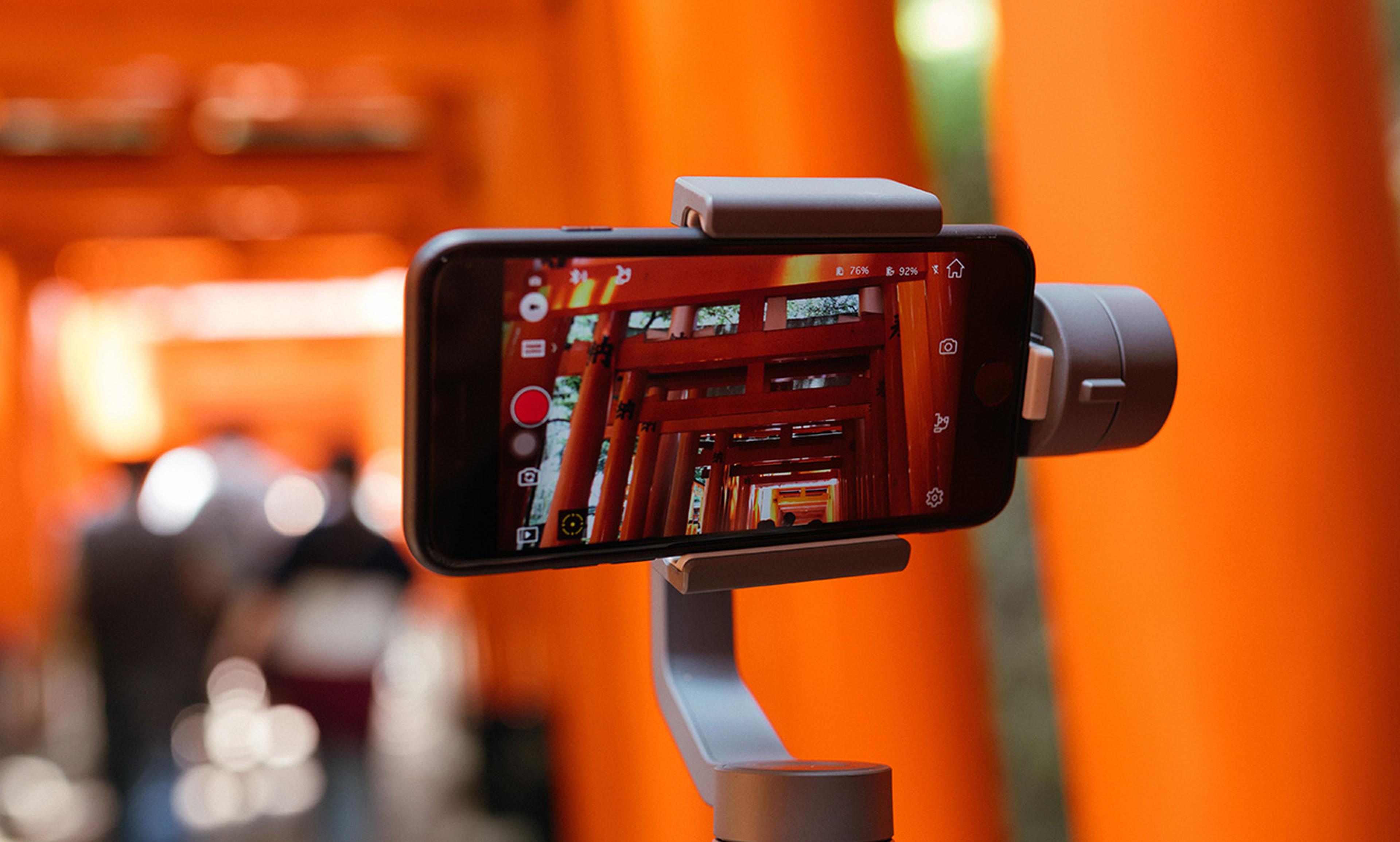 Smartphone auf einem Gimbal, das leuchtend orangefarbene Torii-Tore aufnimmt