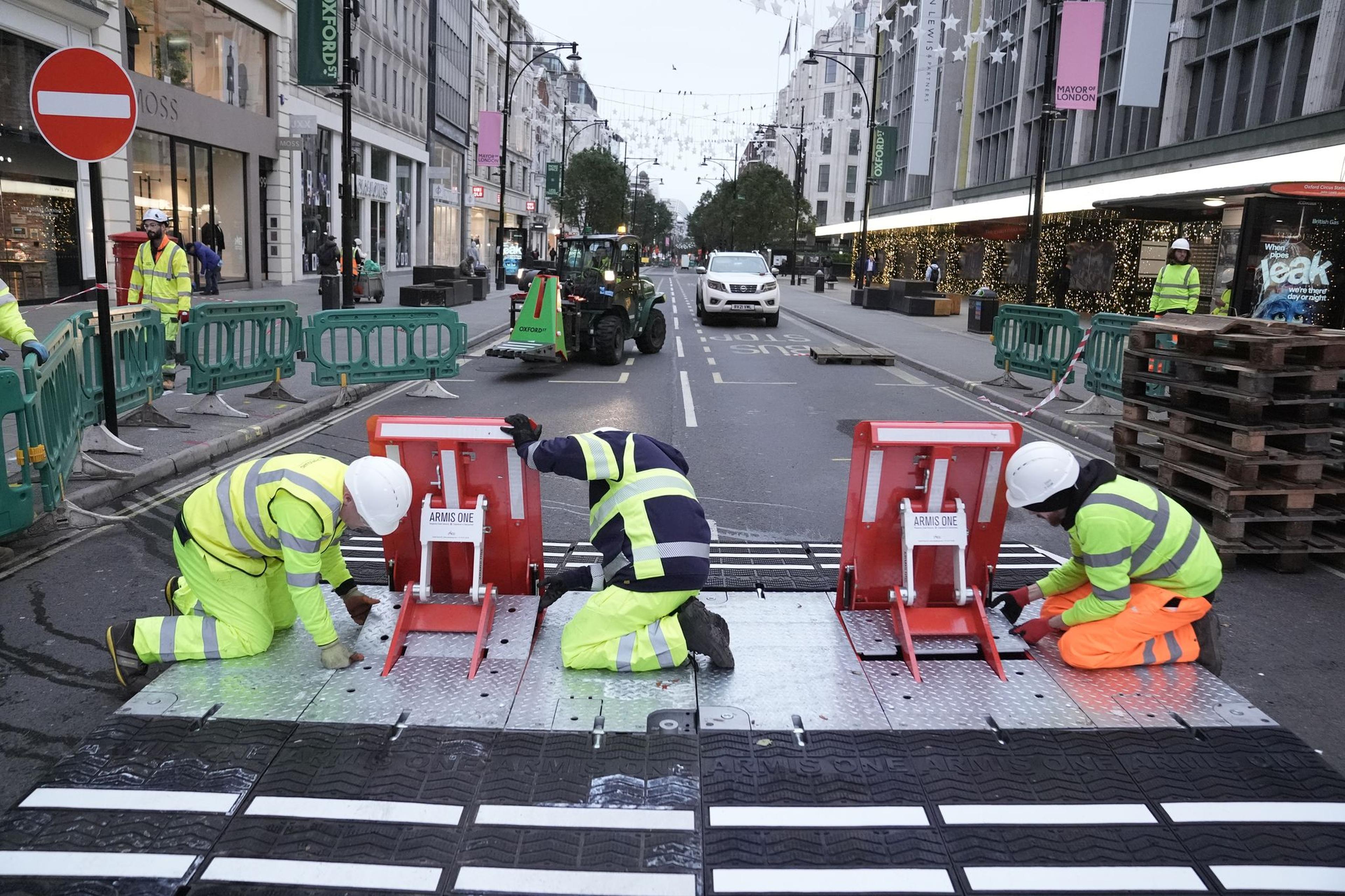 Arbeiter setzen Durchfahrtsperren in der Oxford Street, da die Umwandlung der Straße in eine Fußgängerzone in Kraft tritt. Der Abschnitt der Oxford Street zwischen der Orchard Street und der Great Portland Street wird für private Kraftfahrzeuge, Busse, Taxis, Mietwagen, Fahrräder, Roller und Fahrradrikschas gesperrt.
