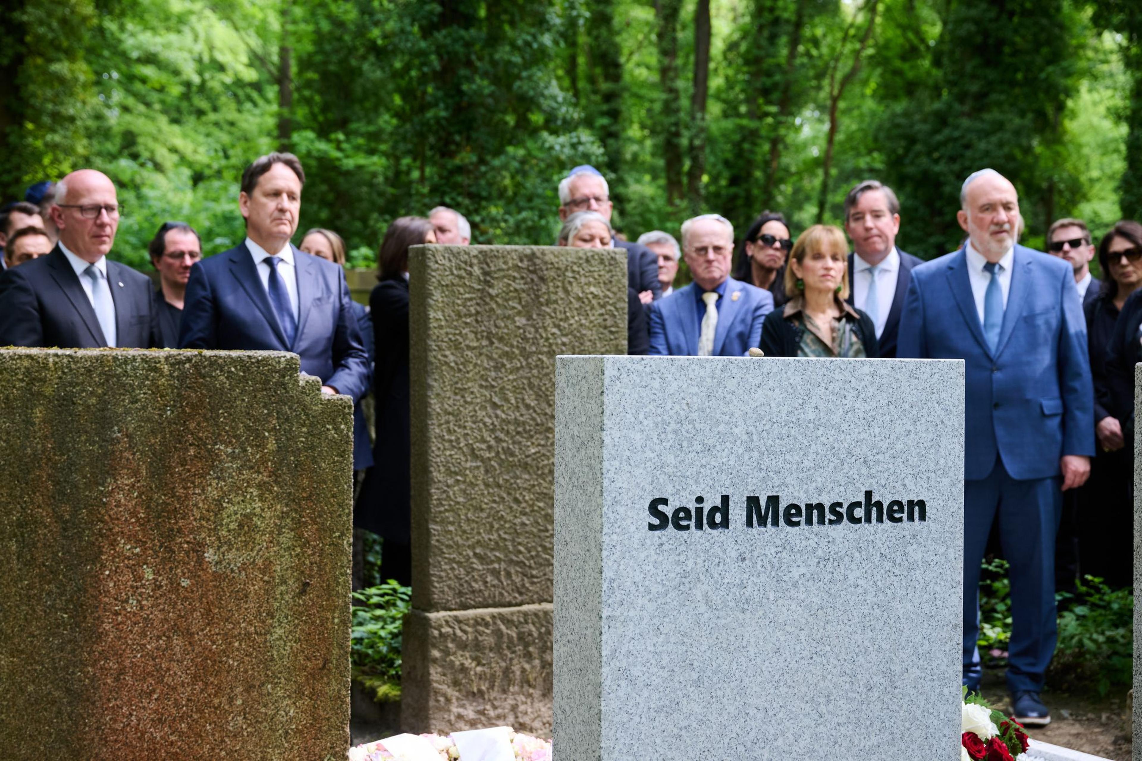 "Seid Menschen" steht auf dem Grabstein Margot Friedländers, während Kai Wegner (l, CDU), Regierender Bürgermeister von Berlin, Karsten Dreinhöfer (2.v.l), Vorsitzender der Margot Friedländer Stiftung, und Ron Prosor (r), Botschafter von Israel, an der Gedenkveranstaltung zum Todestag Friedländers teilnehmen.