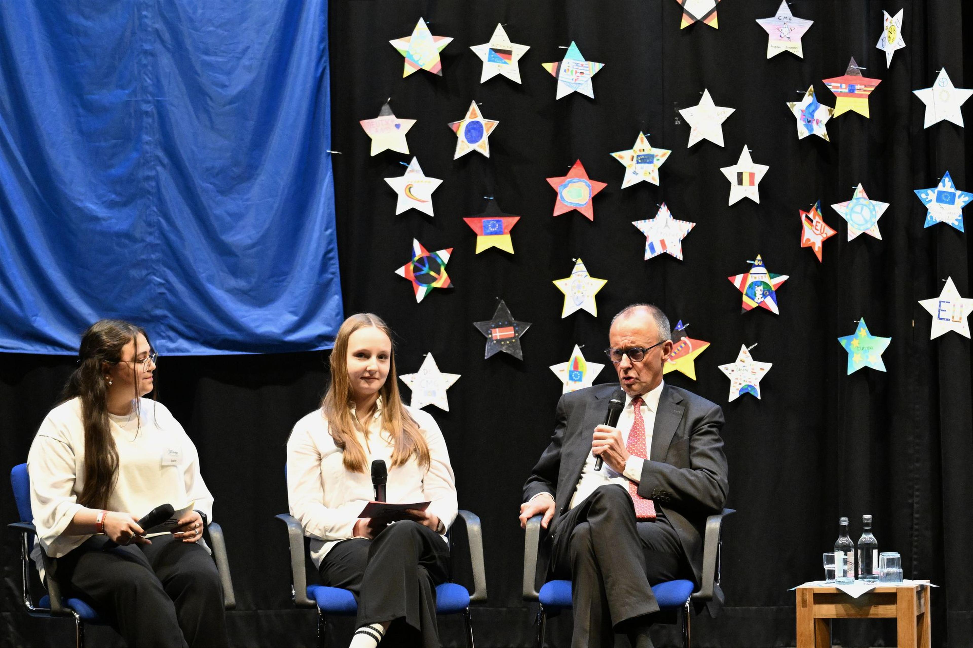 Bundeskanzler Friedrich Merz (CDU, r) besucht das Carolus-Magnus-Gymnasium und nimmt an einer Podiumsdiskussion mit Schülerinnen und Schülern zu Europa-Themen teil.