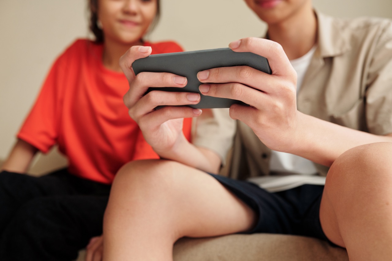Twee jongeren zitten op de bank en kijken naar een smartphone