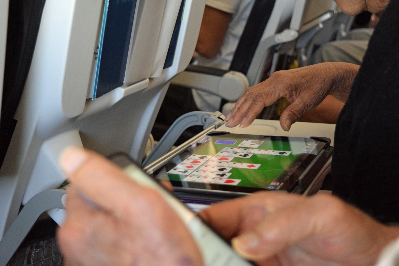 Man speelt Solitaire op het een tablet op het vliegtuig