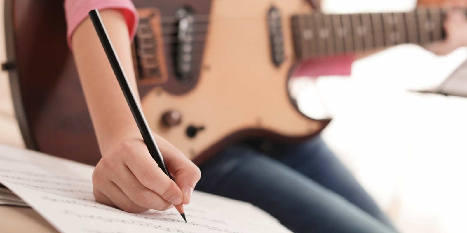 Gitarrist hält Stift zum Notenschreiben in der Hand