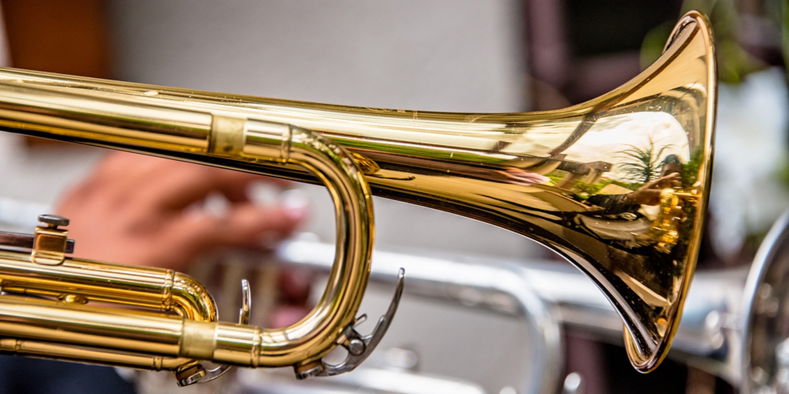 Hand hält eine goldfarbene Trompete