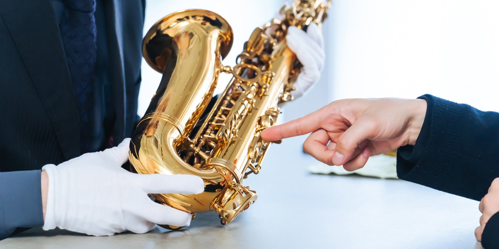 Mann mit weißen Handschuhen hält ein Saxophon