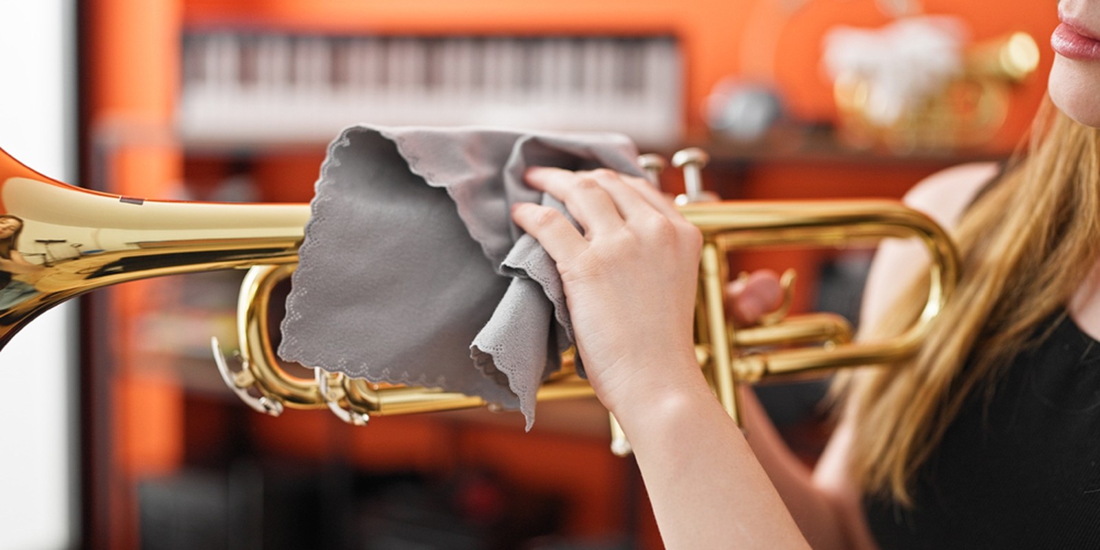 Hand hält eine goldfarbene Trompete mit Reinigungstuch