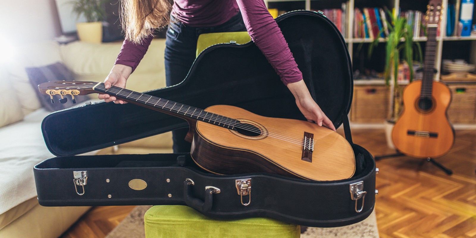 Frau nimmt Akustikgitarre aus einem Koffer