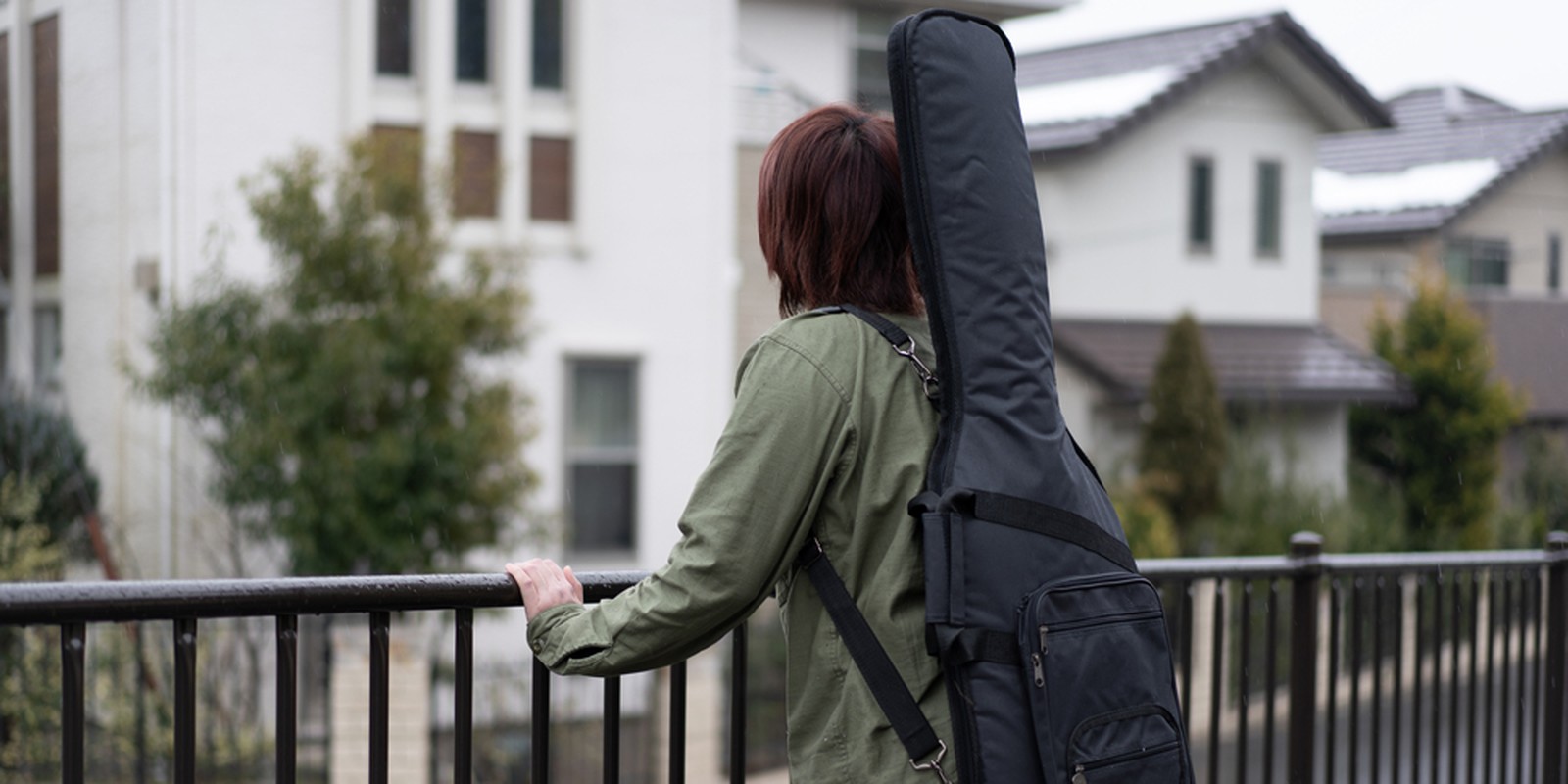 Junger Mann mit Gitarrentasche auf dem Rücken