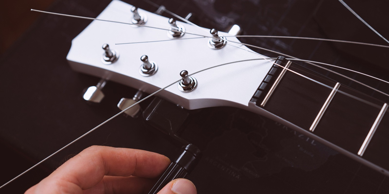 Saiten werden auf eine E-Gitarre aufgezogen