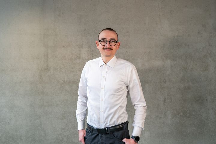 Personalreferent Tobias Gimnich steht zentral im Bild und lächelt.