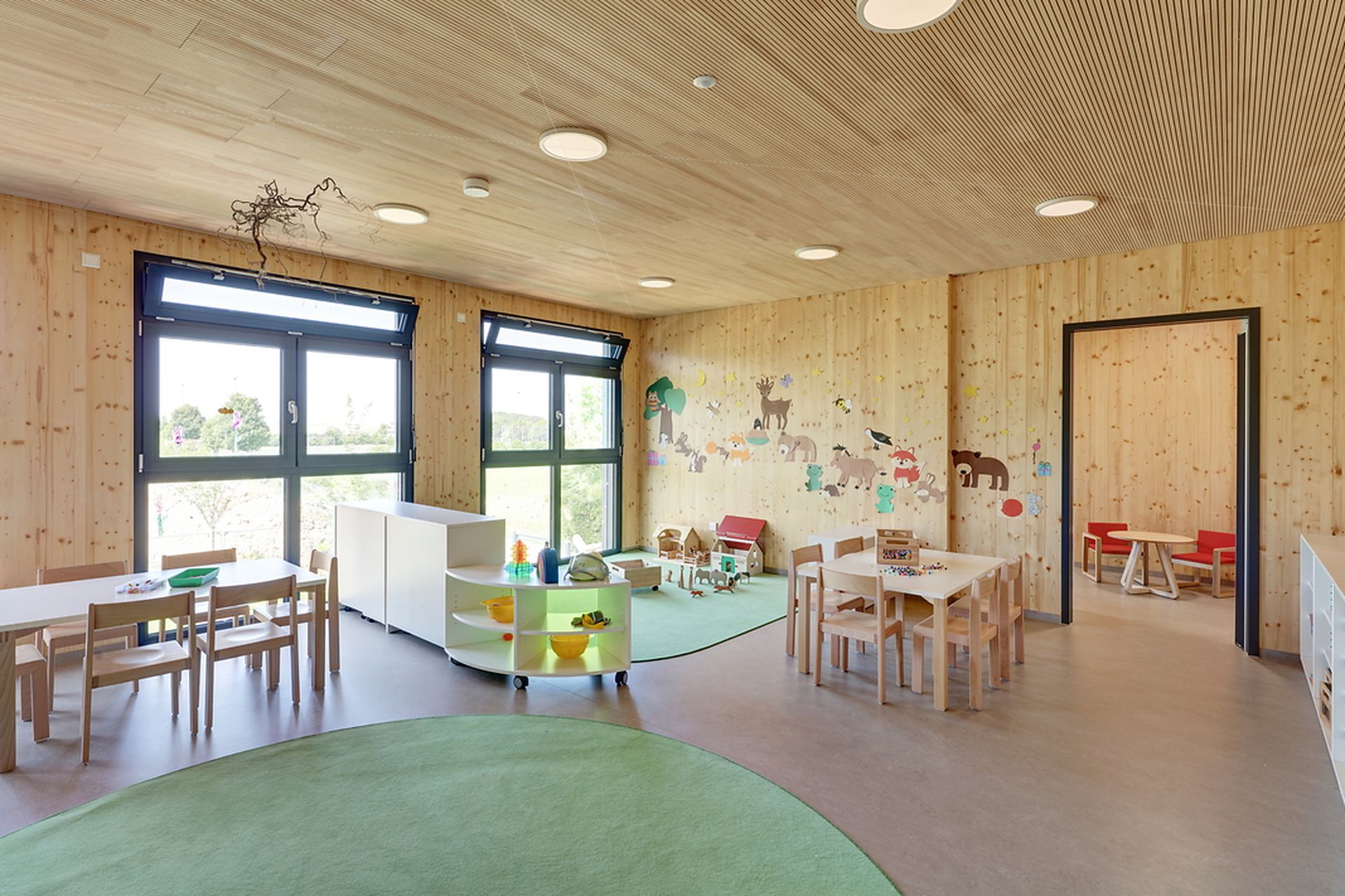 Innenraum Kindergarten Mögglingen mit Gruppentischen und Spielecke.