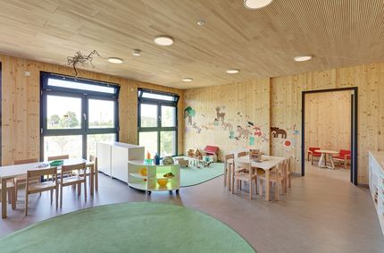Innenraum Kindergarten Mögglingen mit Gruppentischen und Spielecke.