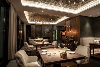 Modernisiertes Restaurant im Travel Charme Ifen Hotel mit stilvoller Einrichtung, gedeckten Tischen und warmem Licht.
