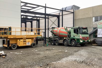 Ein Betonmischer der Firma Geiger vor der Stahlkonstruktion des Hallenneubaus