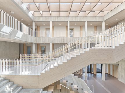 Eine Treppe aus Holz in einem großen hellen Raum mit Tageslichtdecke