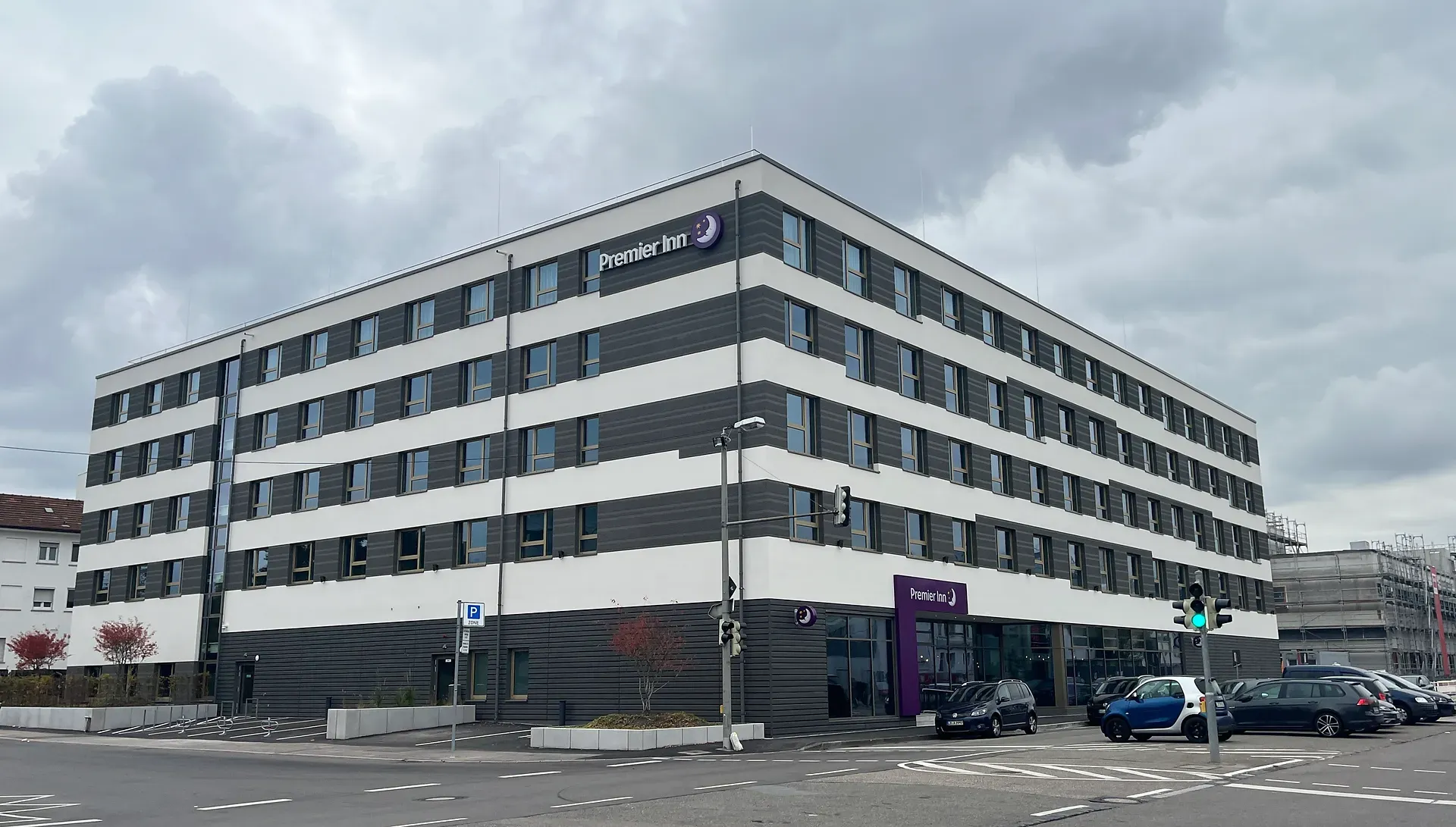 Premier Inn Hotel mit vier Etagen und moderner Architektur in Stuttgart – dunkelgrau-weiße Fassade bei bewölktem Himmel.
