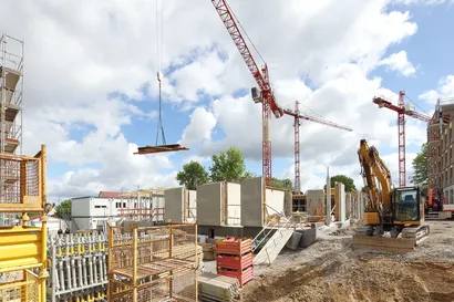 Ein Kran hebt Materialien für den weiteren Ausbauauf der Baustelle an einen neuen Platz.