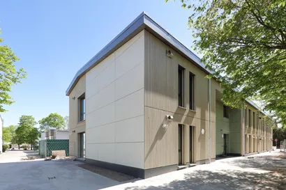 Eiin Haus in Holzmodulbauweise mit einer Fassade aus Holz, ein grüner Baum rechts im Bild.