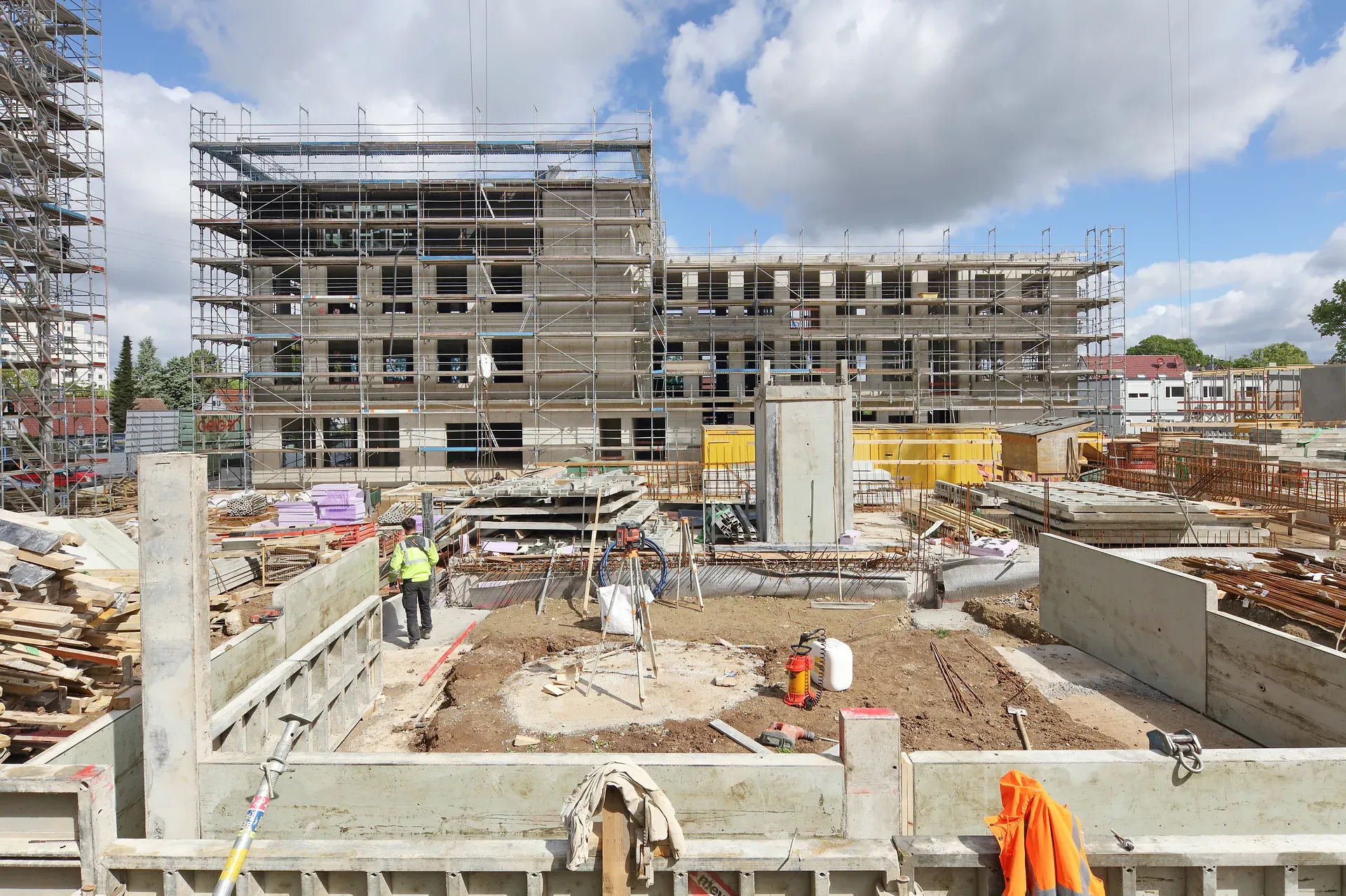 Eine Baugrube mit unterschiedlichen Materialien für den Neubau des Quartier am Rotweg, im Hintergrund ein Haus im Gerüst.