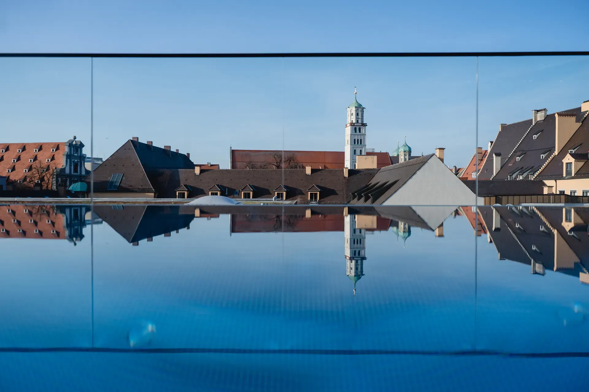 Speigelung des Infinity Pools über den Dächern von Augsburg mit Ausblick auf Augsburg.
