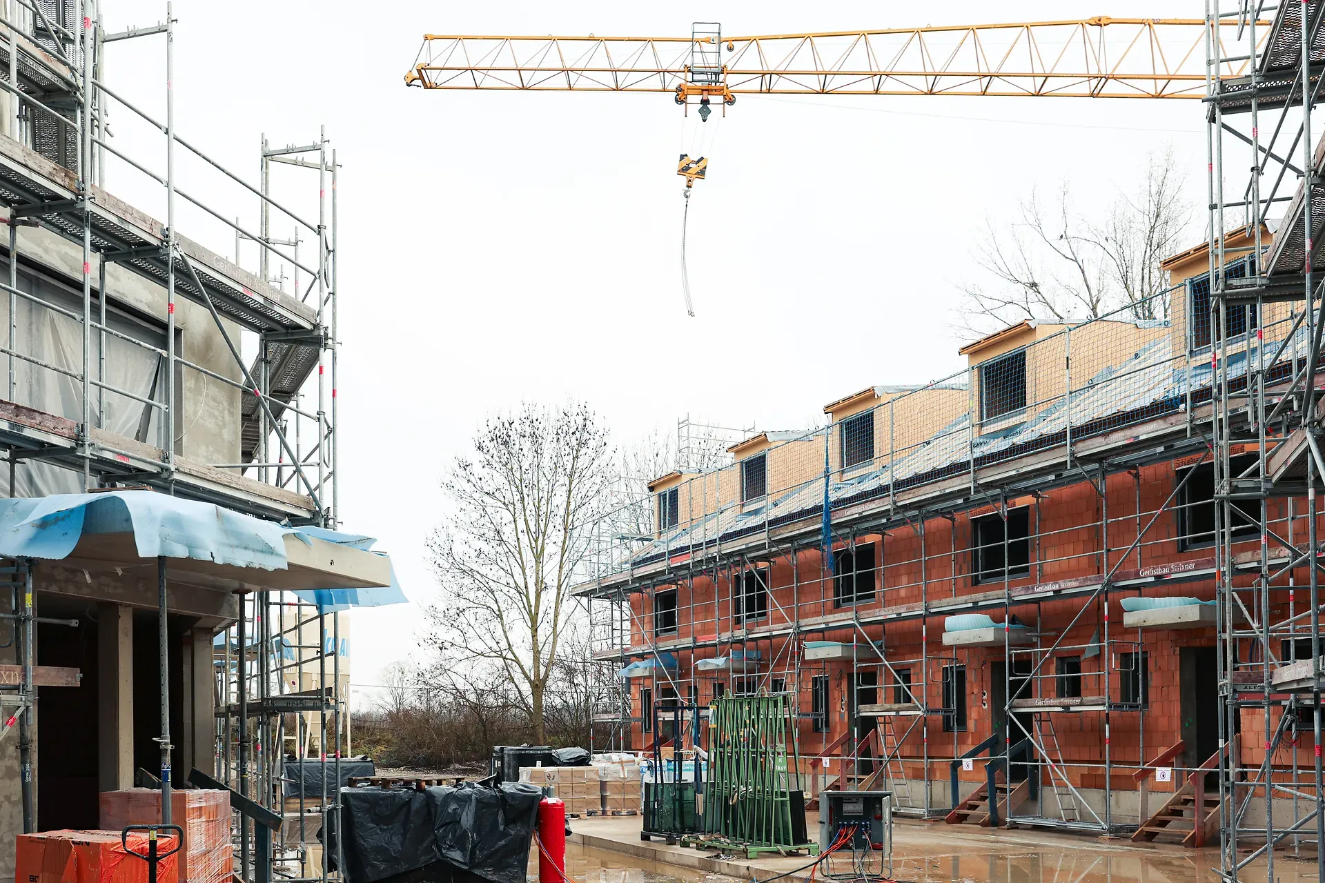 zwei Gebäude im Rohbau mit Gerüsten und Kran