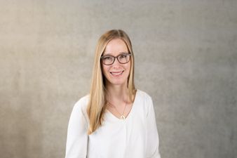 Personalreferent Julia Hindelang steht zentral im Bild und lächelt.
