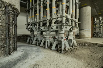 Graue Stützen neben freigelegten Betonstützen, bei welchen man die Bewährungen sehen kann.