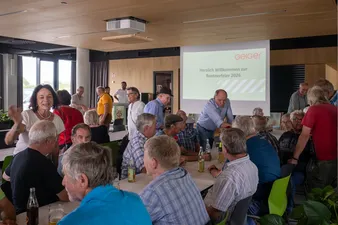 Eine Gruppe an Personen sitzt an einer langen Tafel in der Kantine von Herzmanns 2.