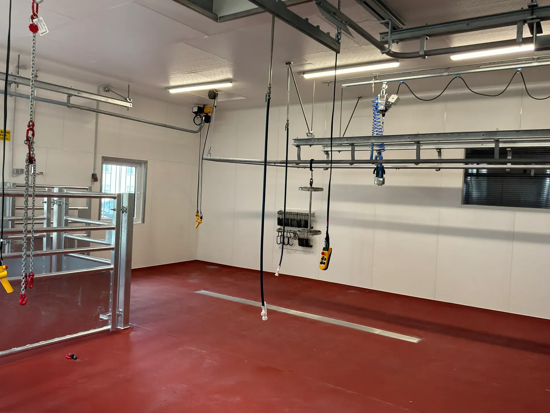 Eine große Halle mit rotem Boden. Von der Decke hängen Steckdosen und vreschiedene Ketten.