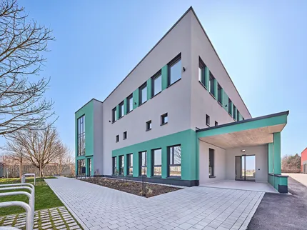 Würfelförmiges Gebäude mit zwei Stockwerken in den Farben grün und grau.